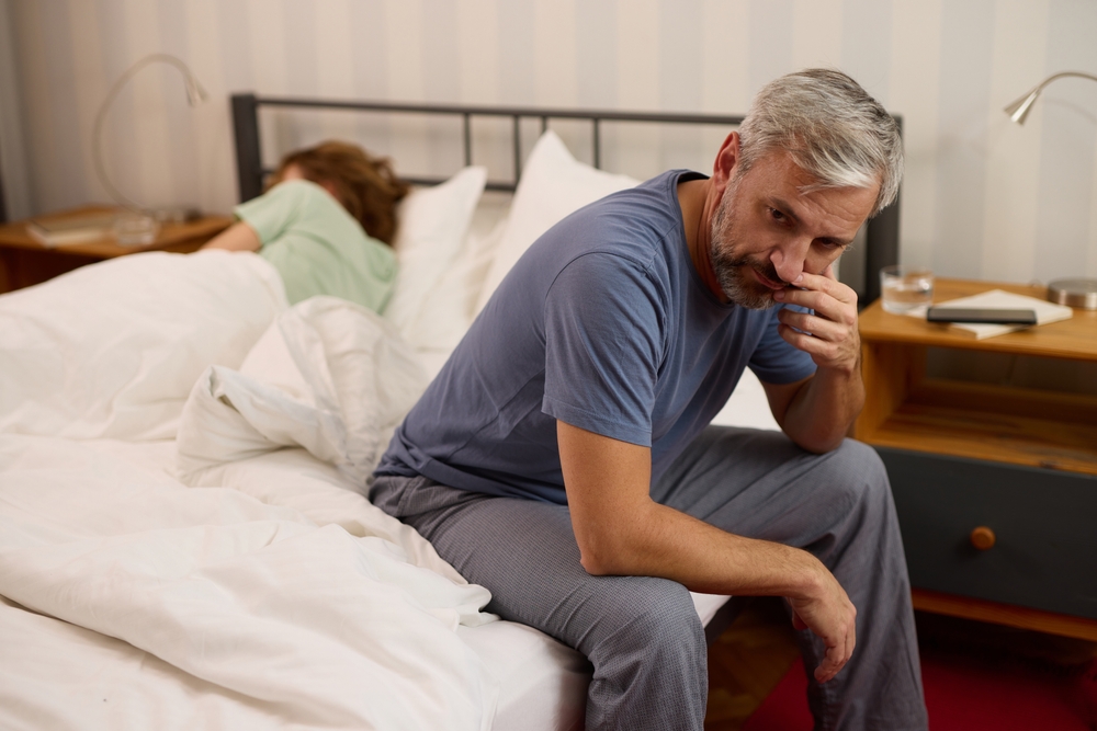 Mature,Man,Looking,Worried,While,His,Wife,Sleeps,In,The