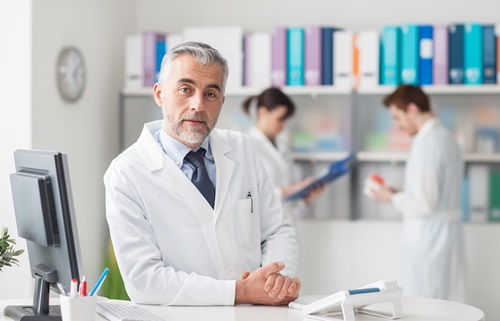 Doctor,At,The,Reception,Desk,Looking,At,Camera,,Healthcare,Concept